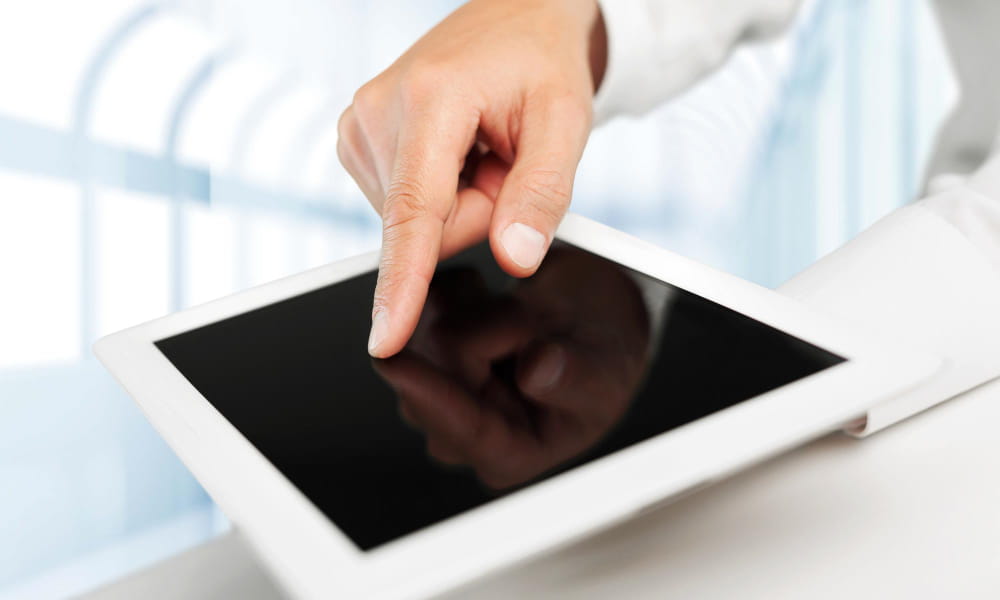 Gros plan sur un utilisateur naviguant sur un tactile écran de tablette numérique blanche