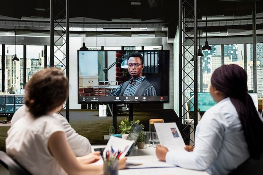 Des professionnels participent à un blockchain forum international via une visioconférence dans un bureau moderne.