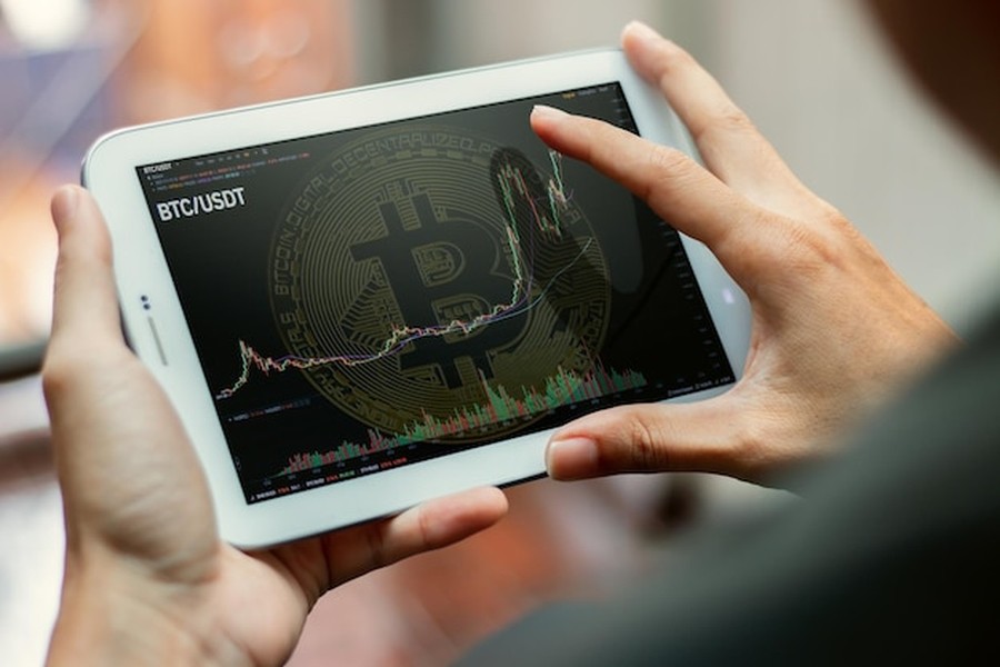 Un investisseur analyse un graphique de trading BTC/USDT sur une tablette pour suivre les tendances du blockchain boursorama forum.
