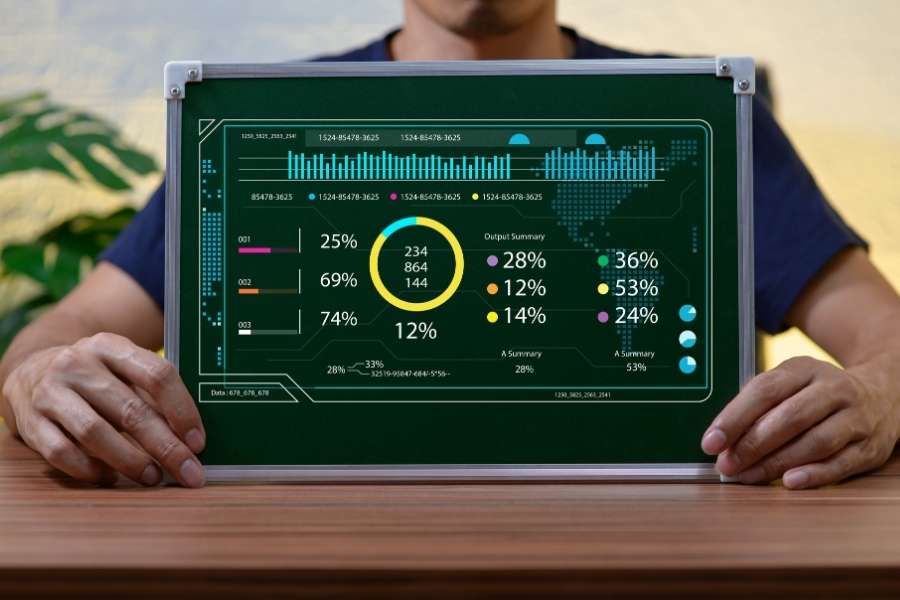 Un homme présente un tableau vert affichant des données et des graphiques numériques.