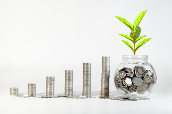 Croissance financière illustrée par des piles de pièces croissantes et une plante dans un bocal, symbolisant l'investissement programmé.