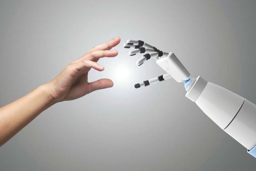 Une main humaine et une main robotique chromée se serrent la main, illustrant l'avenir de la robotique.